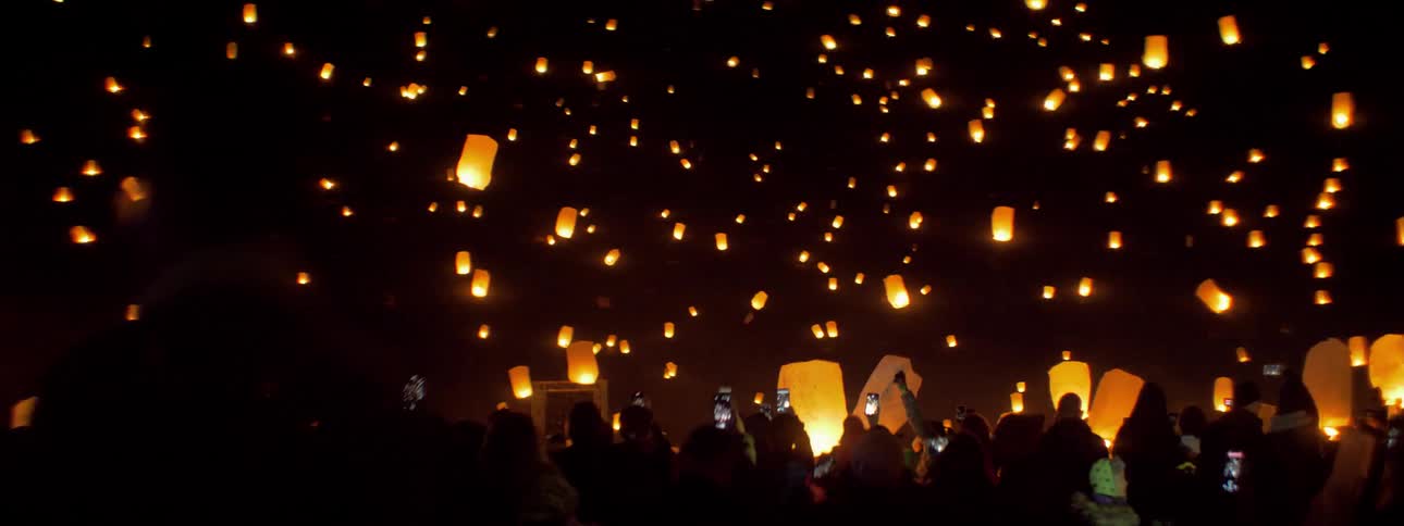 People letting paper lanterns fly into the night