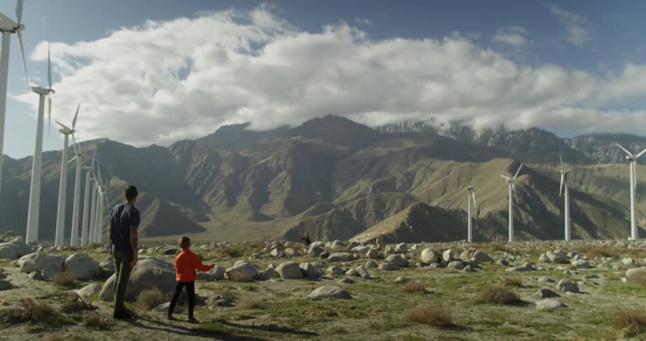 A man throws a football to a boy in a rocky field