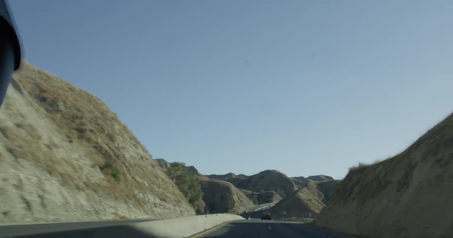 Traveling view of highway lined with mountains