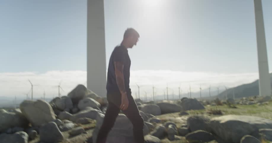 A man throws a football to young boys while standing next to wind turbines