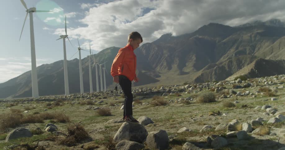 A boy jumps around on some rocks on a field