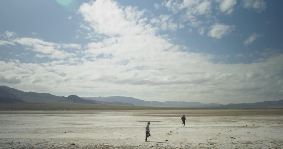 A couple of people playing and running in the desert