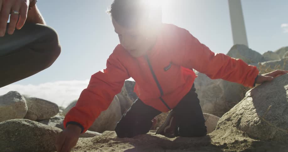 A boy uses a rock to draw in dirt