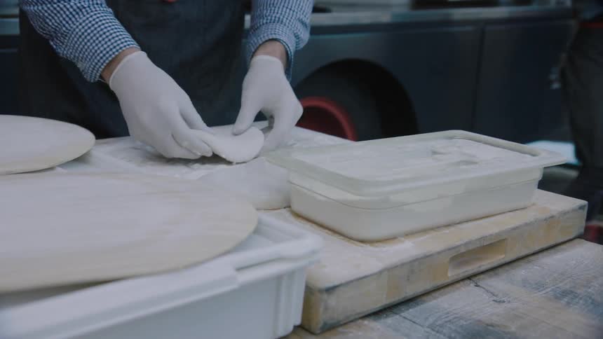 A person flours some dough and then begins to press it out