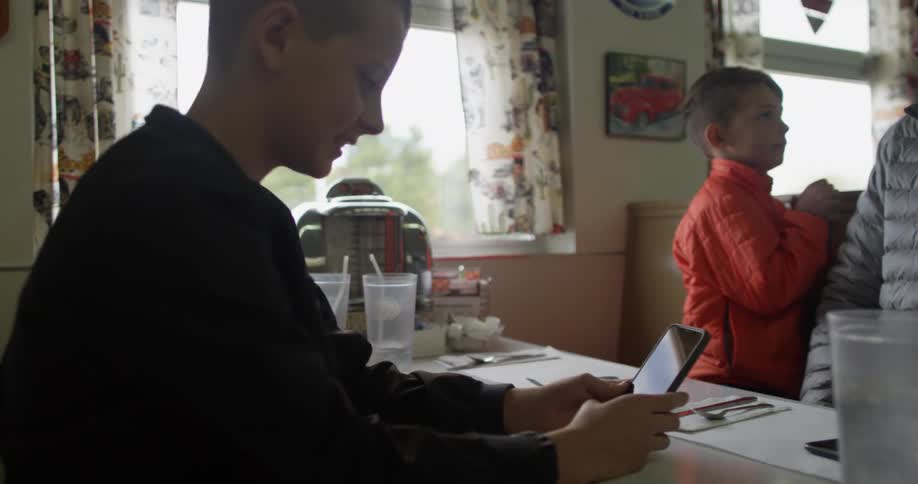 Man and boys sit at a diner booth