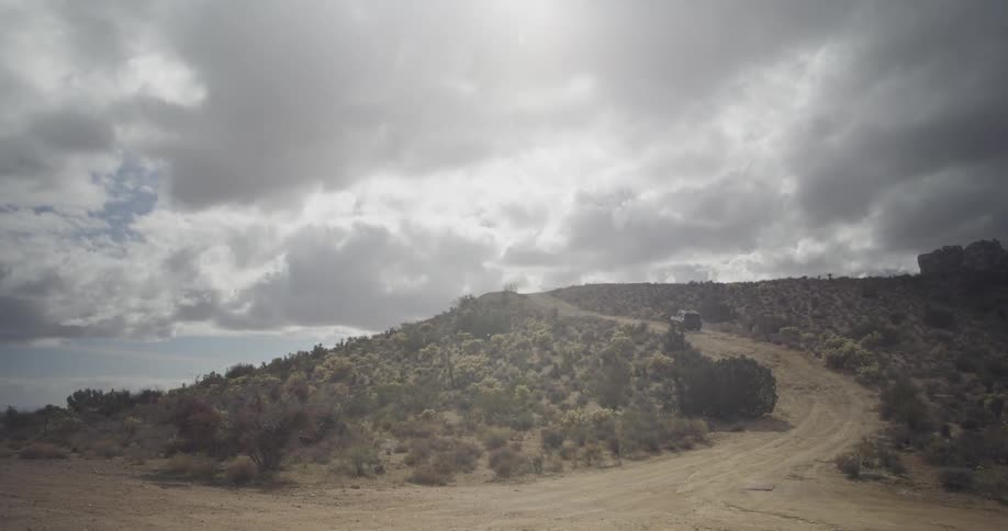 An suv drives up a dirt road on a hill