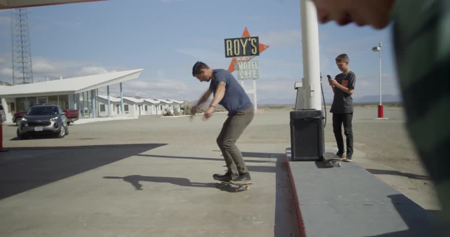 A child records a man riding a skateboard