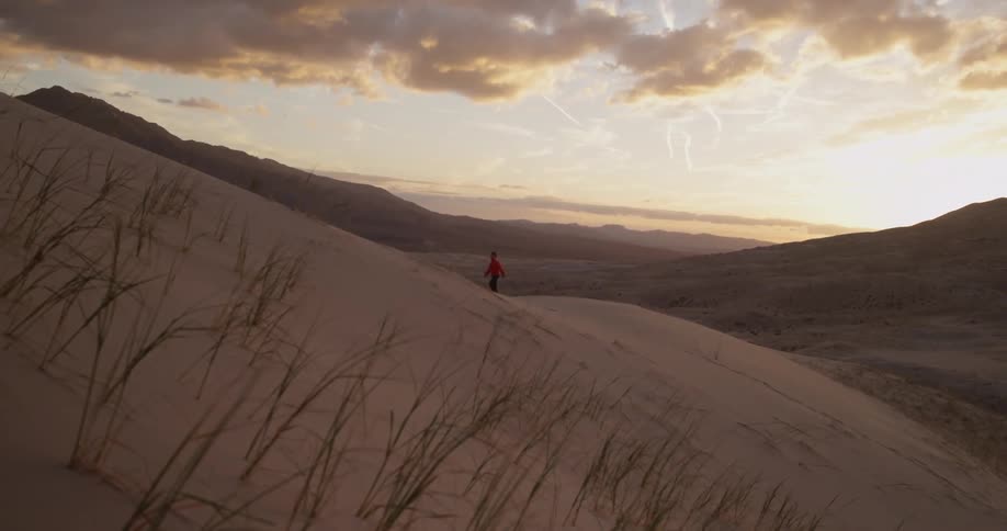 Person hikes up sandy dunes on a cloudy day