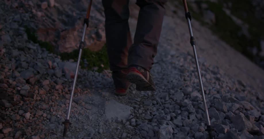 A man hikes on a rocky path in the mountains