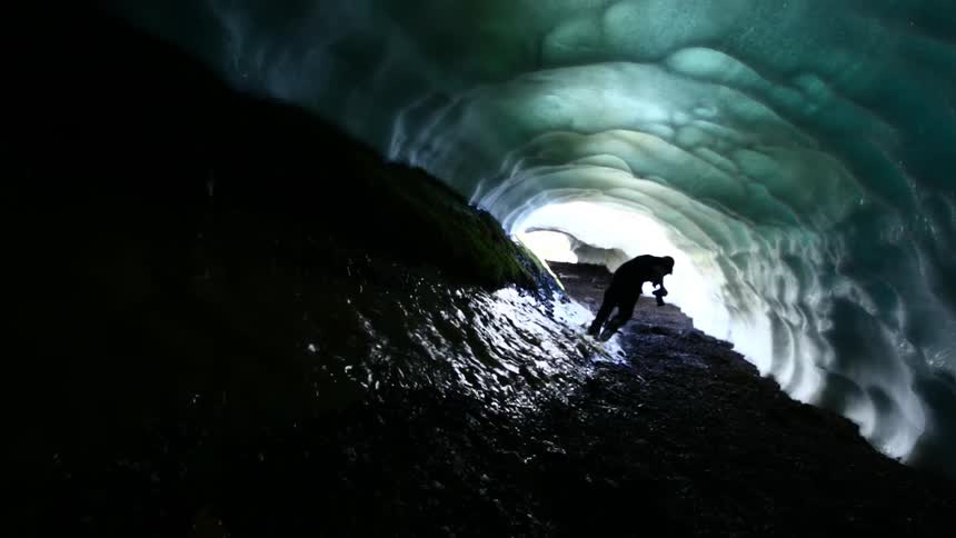 A man carrying a camera runs through a tunnel