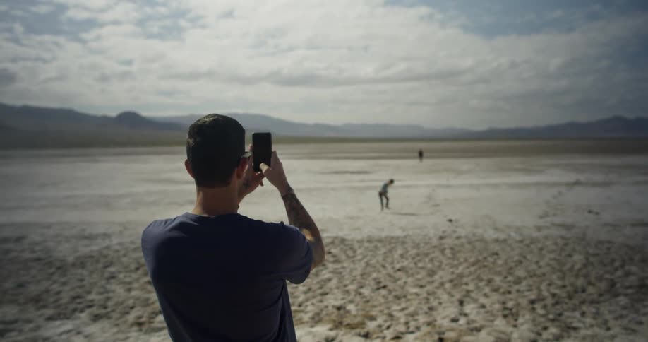 A man photographs a young child with his phone