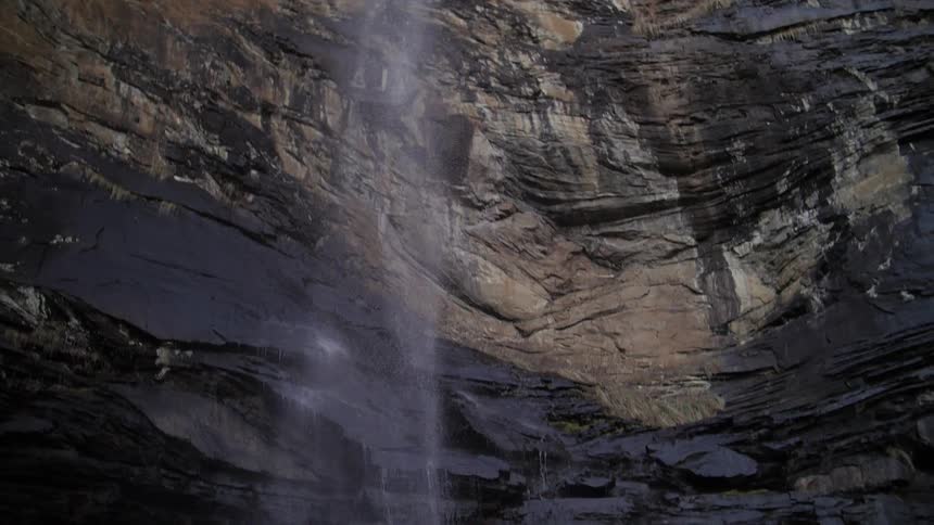 A waterfall cascades over a steep cliff onto a rocky ledge below