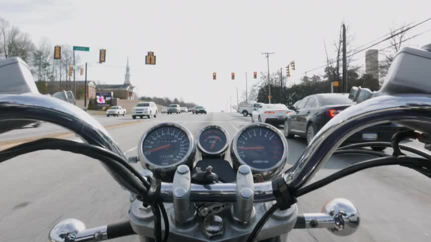 Motorcycle with silver handlebars travels down the street