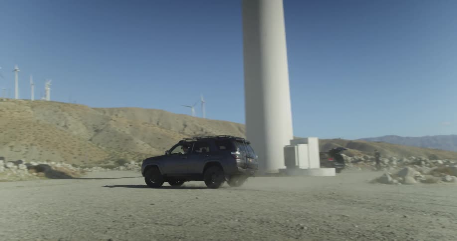 Vehicle drives past a row of tall windmills