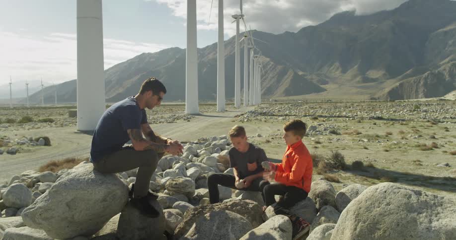 Children play with rocks as a man watches