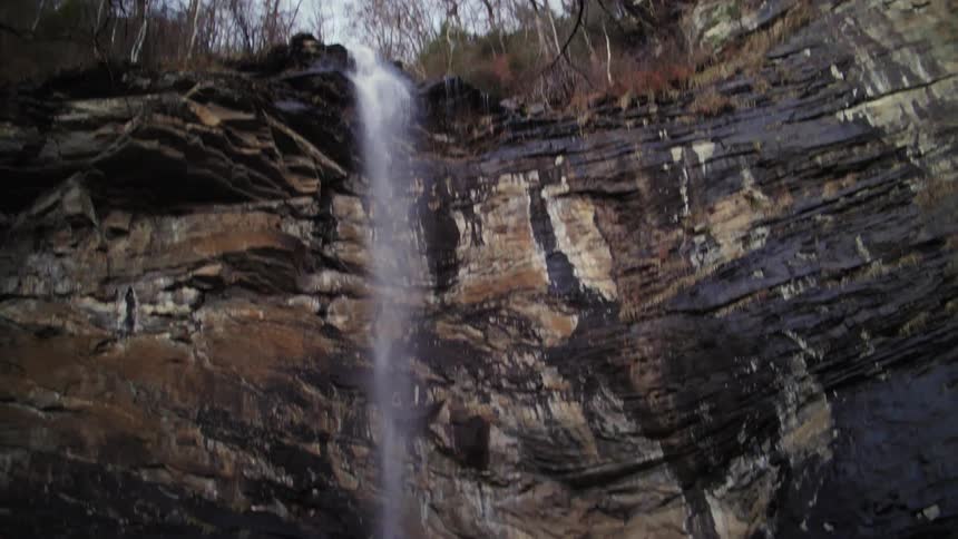 A waterfall streams over a cliff edge onto rocks below