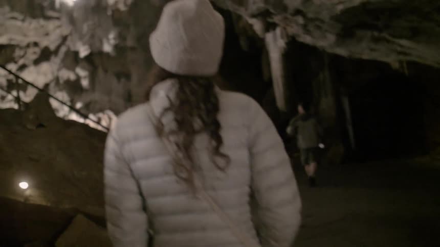 A woman walks through a cave