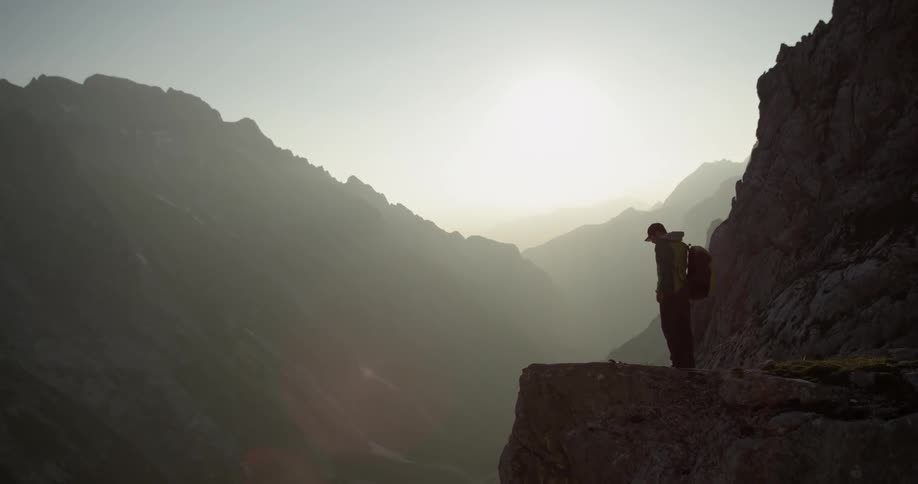 Person walks at the edge of a cliff and stops to look