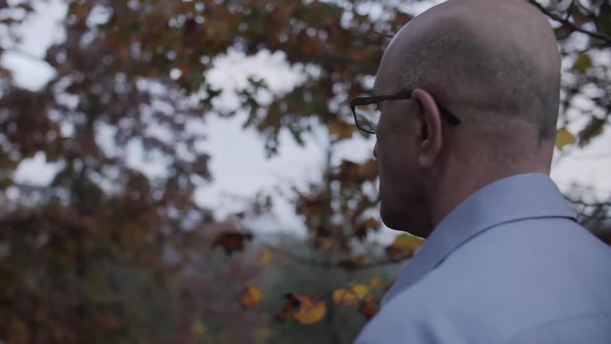 An older man looks out at a view as he walks forward