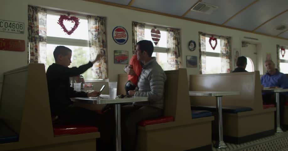 Man and two boys sitting in a booth at a restaurant