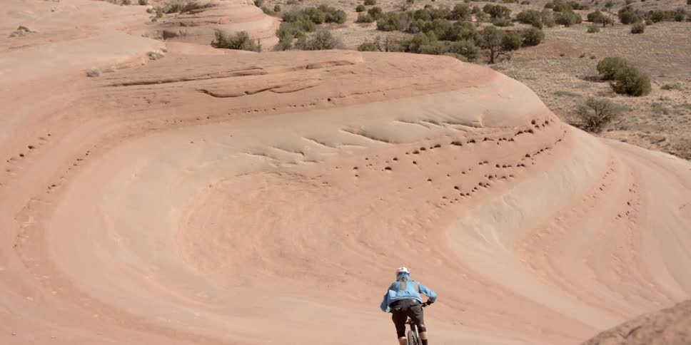 A bicyclist jumps and rides on a rock formation in the desert