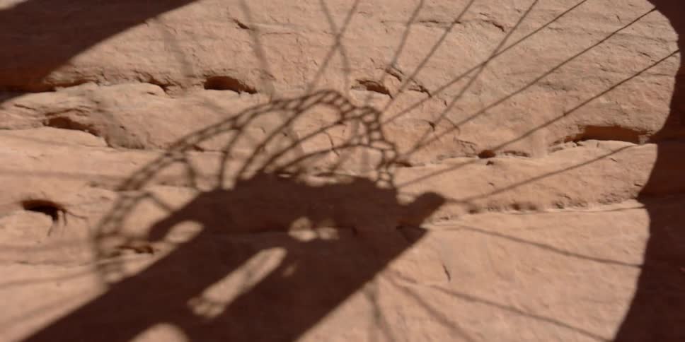 A bicycle tire shadow reflects on red stone