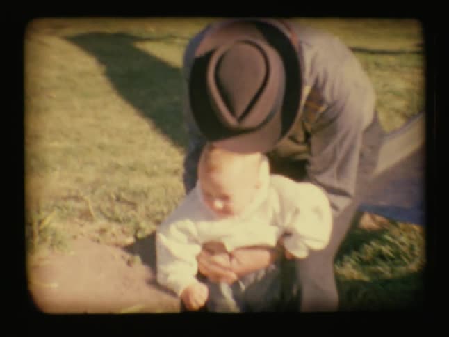A man rides down a slide holding a baby