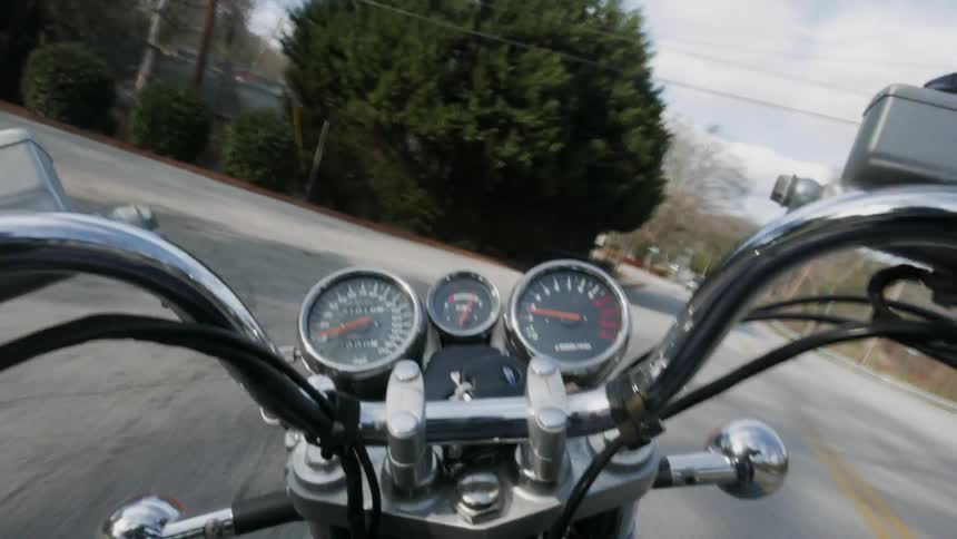 Traveling view of a motorcycle going down a road and into a garage