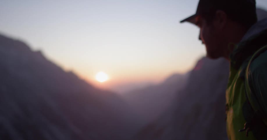 A man is hiking on a mountain at sunset