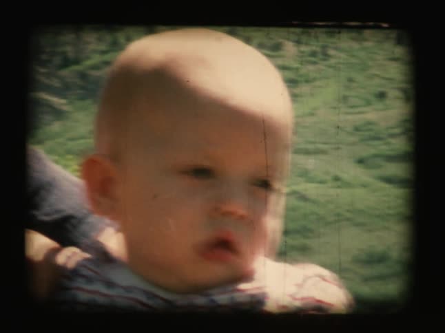 A woman holds a baby outside on a sunny day