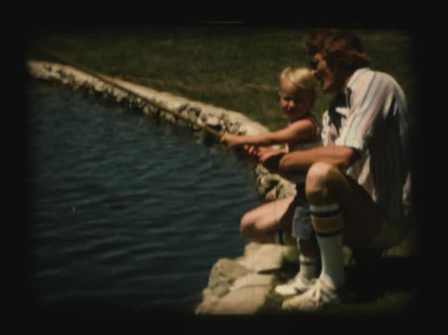 A man helps a little boy fish