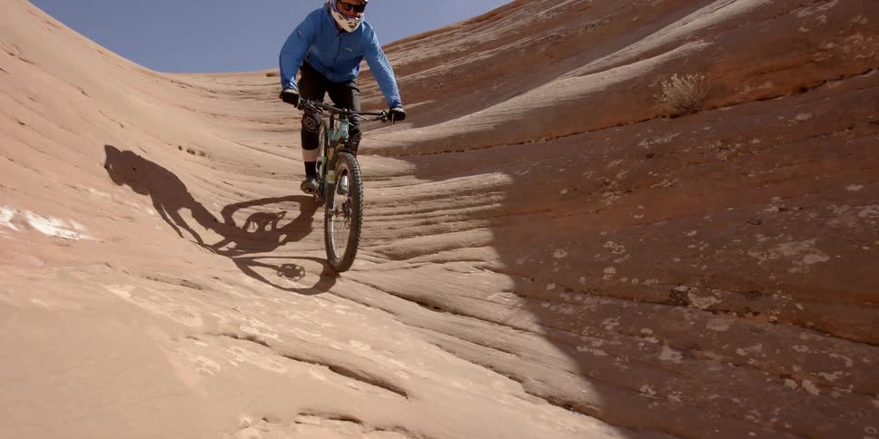 Bicyclists ride down rock formations in the desert