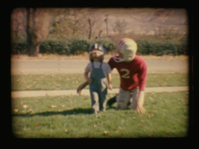 A boy and a young child play with football hats on