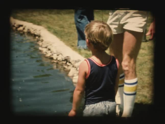 Men and boys fish at a pond on a sunny day