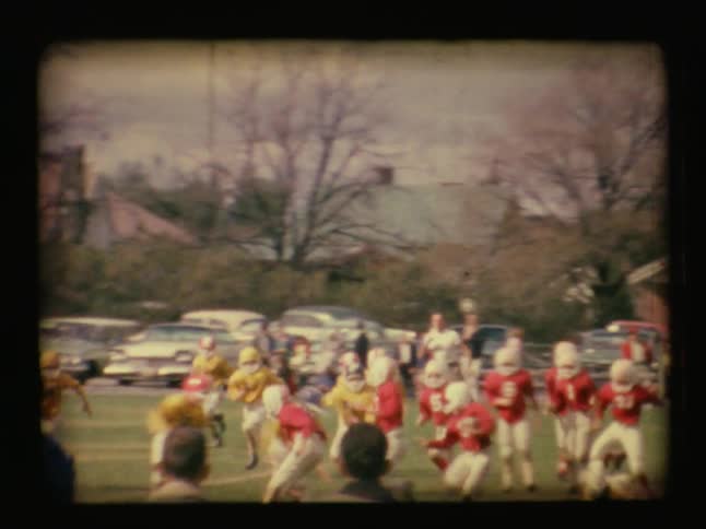 Boys play football on a grassy field