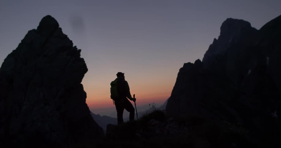 A man is hiking on a mountain at dawn