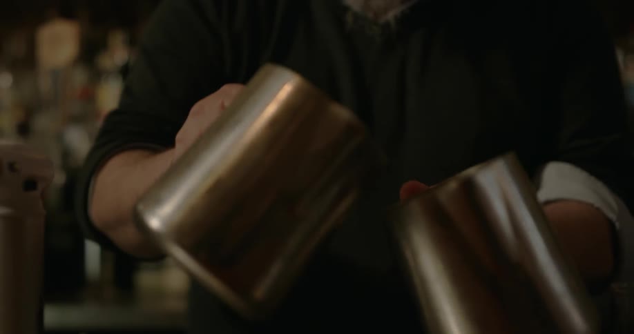 A man sets a cup of liquid on fire then pours it into another cup