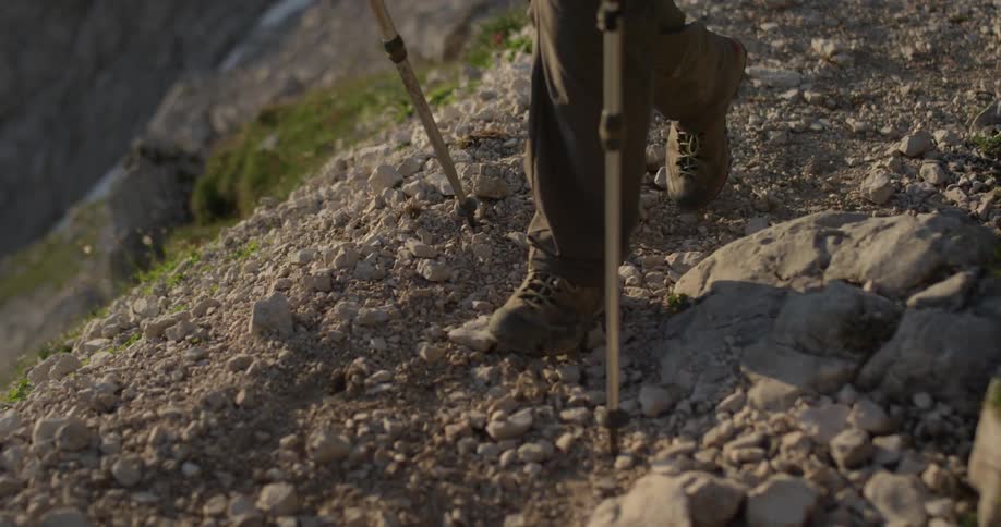 A hiker walks on a rocky path in the mountains