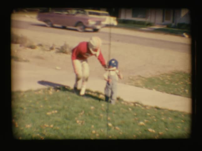 A young boy chases down a toddler running towards the road