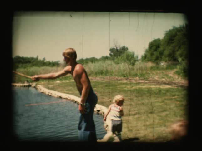 A man and boy are fishing near a pond