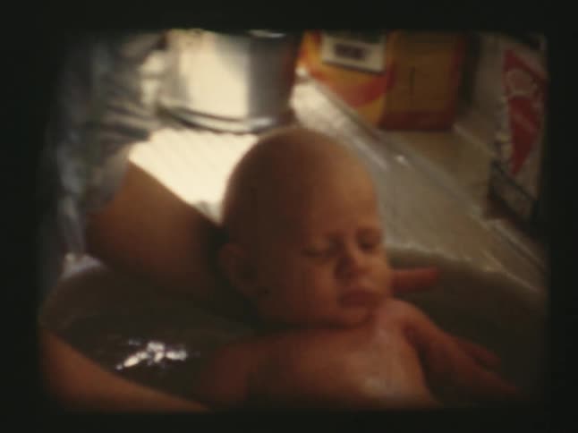 A baby is being bathed in a small sink