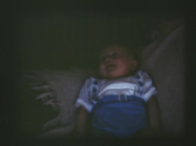 Baby laying on a blanket with an adult nearby
