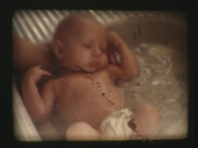 Person bathing an infant in a small tub