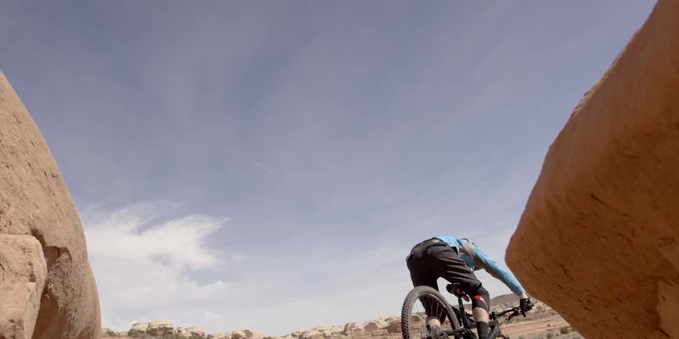 Person riding a bike over a cliff in the desert