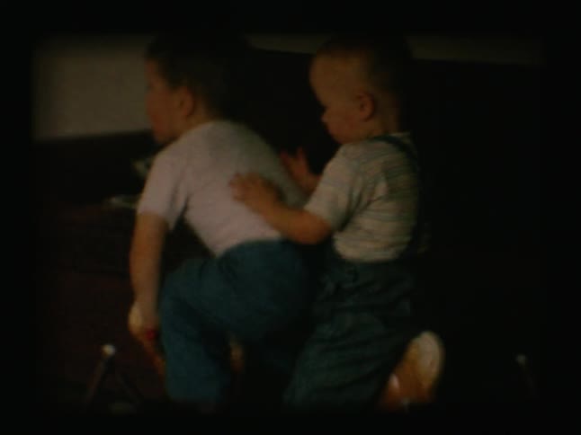 Two young boys play on a bouncy horse toy