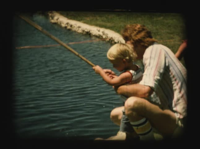 A man helps a young boy to fish