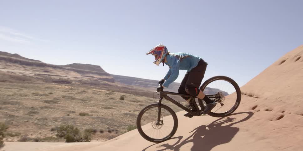 A man jumping a bike off of large rocks in the desert