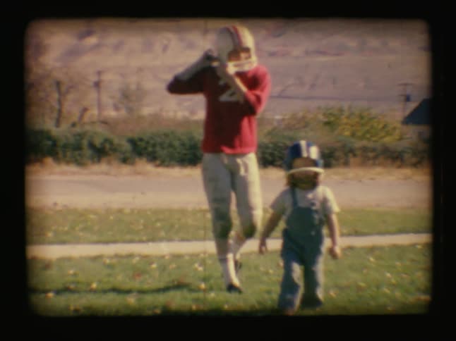A boy and a young child play with football hats on