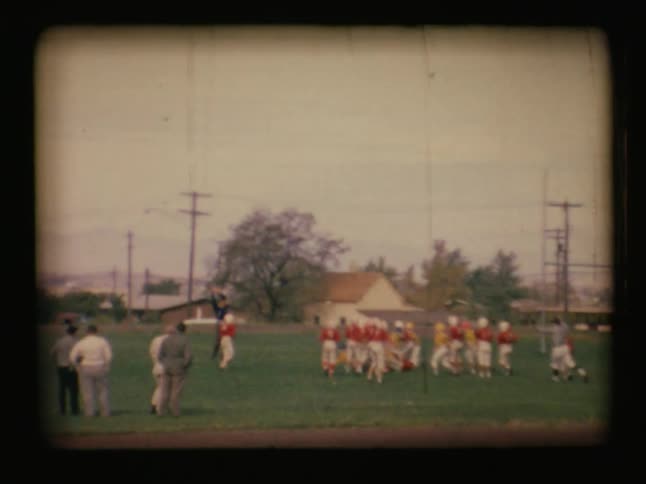 Boys play on opposing football teams on a grassy field