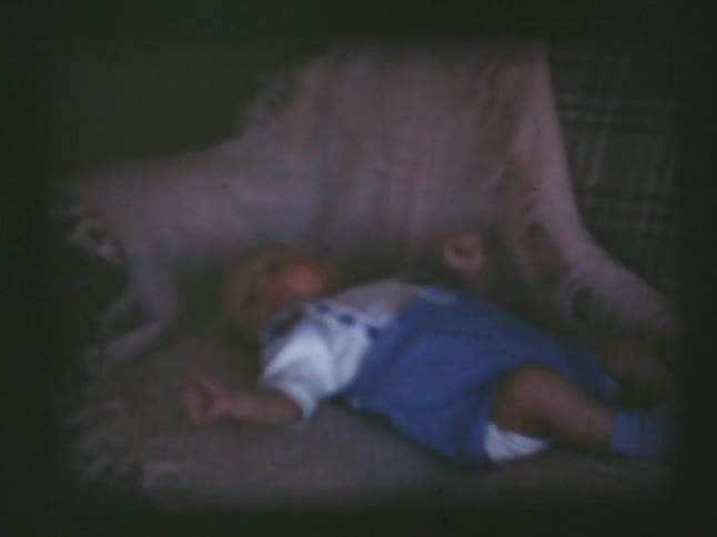 A baby lays on a blanket draped over a couch